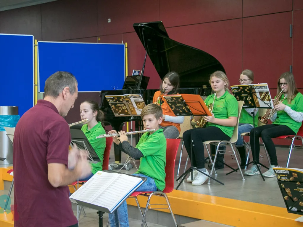 Dirigent leitet das Schulorchester im Foyer.